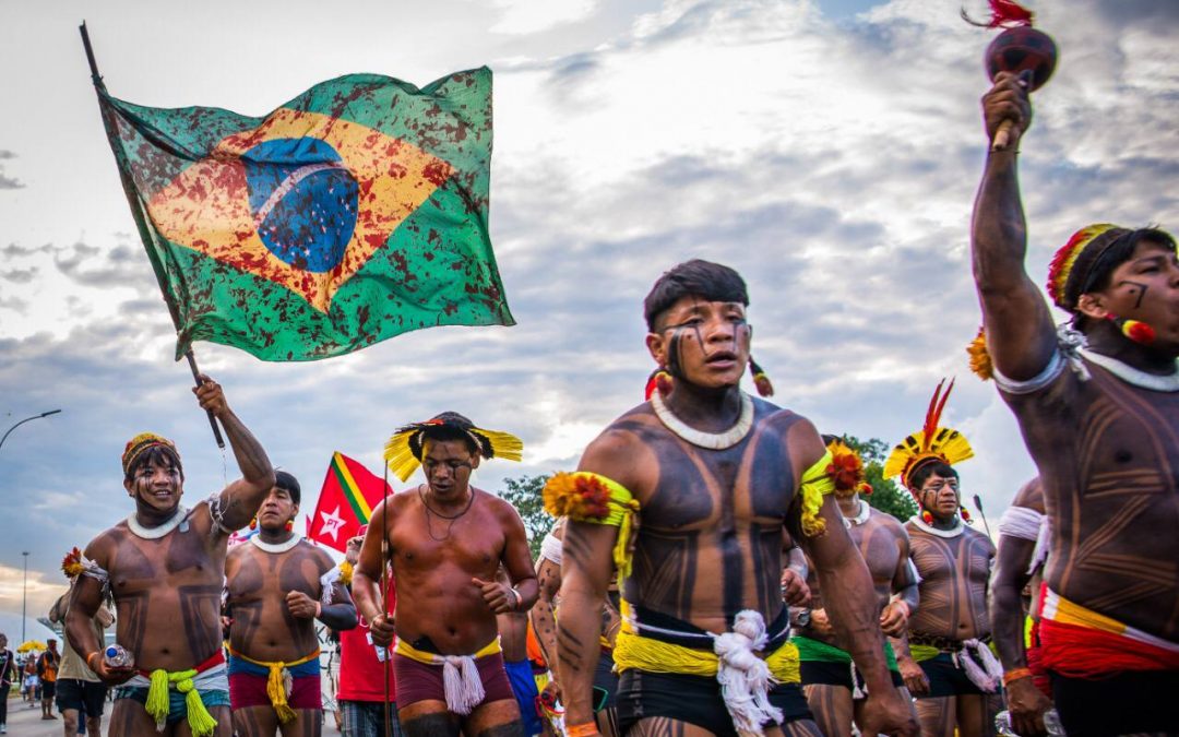 Índios dançando e segurando a bandeira do Brasil